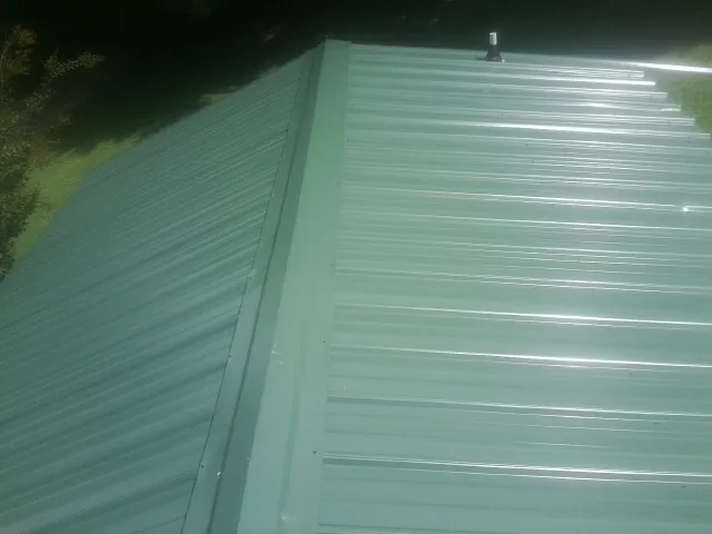New green metal panels meeting at the ridge of a roof — Flat Roof Repair work by our crew in Camano Island