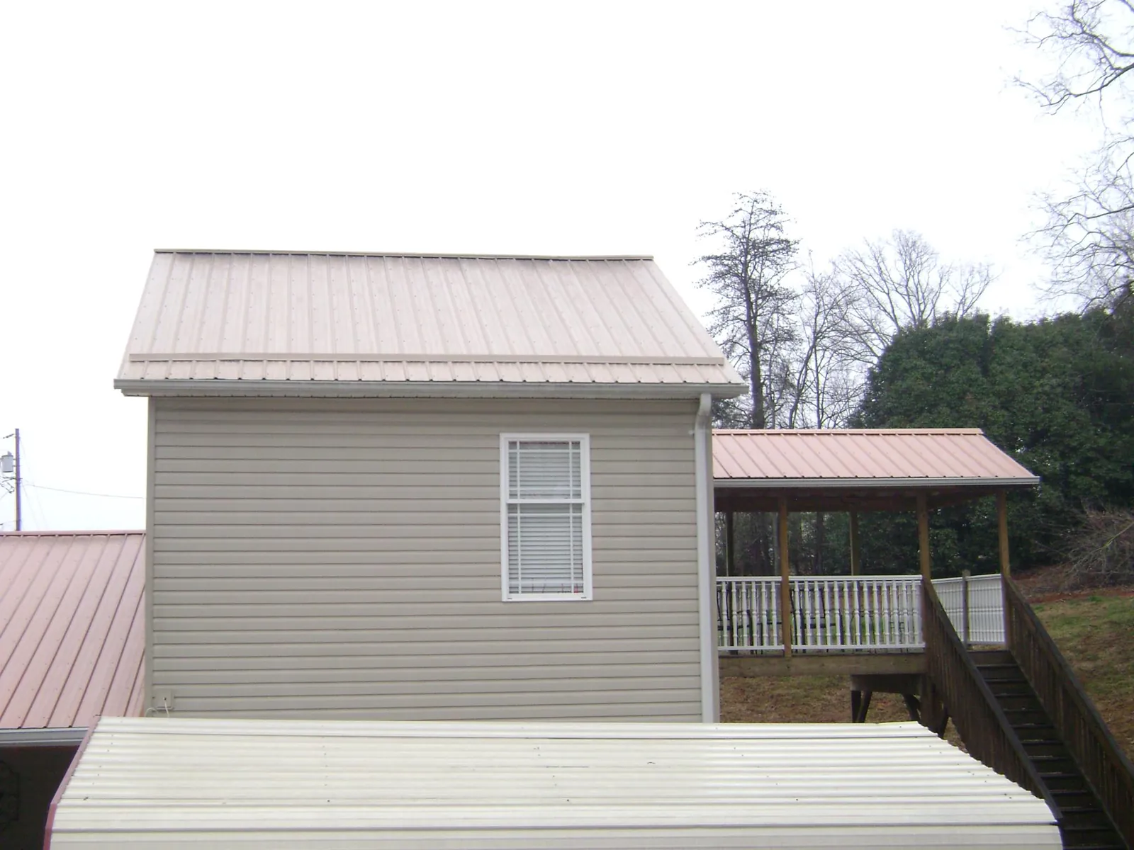 Tan metal roofs on a two story addition and attached porch, from a Roof Replacement job in Camano Island