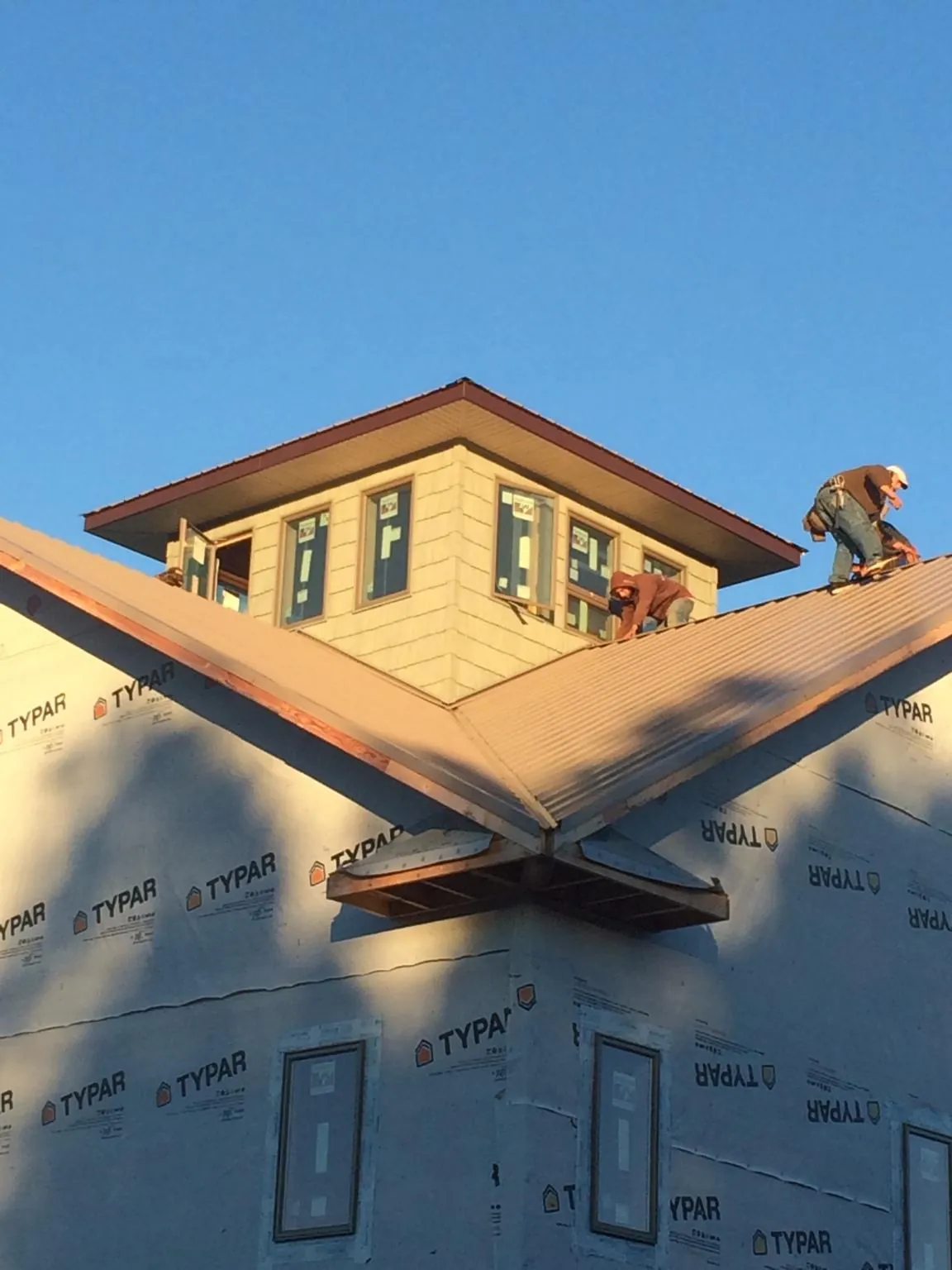 Roofers working around a rooftop cupola on a new metal roof at sunset — Roof Waterproofing in Camano Island by Roofing Brothers